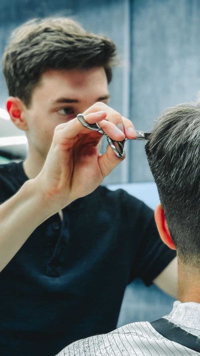 Mastering the First Impression: Your intriguing post title goes here Barber skillfully cutting a customer's hair in a contemporary barbershop setting.
