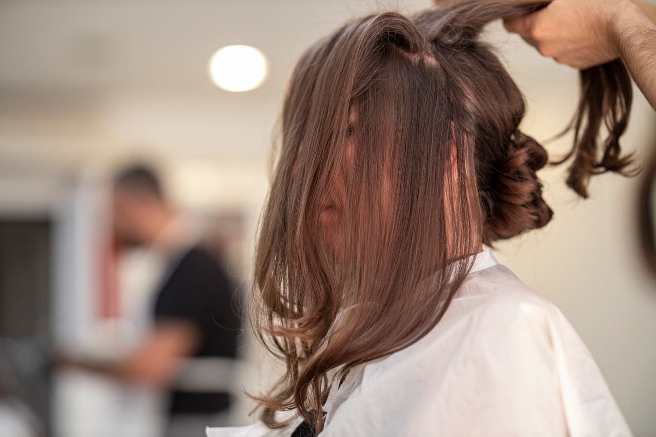 The Art of Drawing Readers In: Your attractive post title goes here Side view of a woman getting hair styled by hairstylist in a modern salon setting.