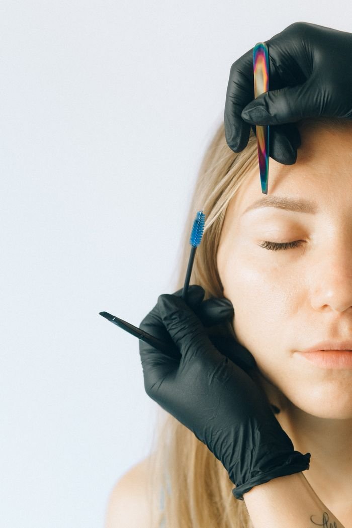 Offerings Close-up of a woman receiving professional eyebrow and lash treatment in a beauty salon.