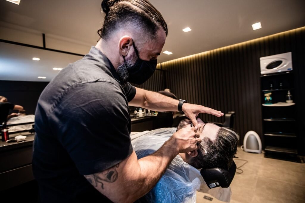 Crafting Captivating Headlines: Your awesome post title goes here Barber expertly shaves client using straight razor in stylish salon. Captured indoors, showcasing modern grooming.